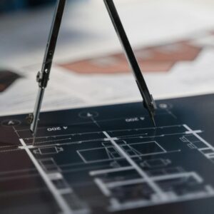 A compass on architectural blueprints, showcasing planning and measurement details.