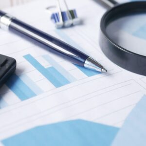 Close-up of calculator, pen, and magnifying glass on financial documents.