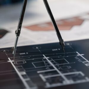 A compass on architectural blueprints, showcasing planning and measurement details.
