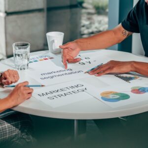 Two adults in an office discussing marketing strategy around a round table.